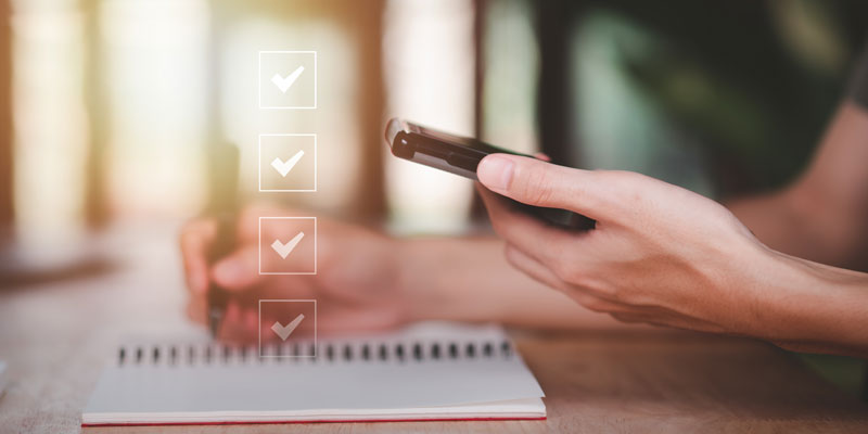 Change of address checklist. Close up of desk showing hands holding a phone and the other using a pen to update a checklist.