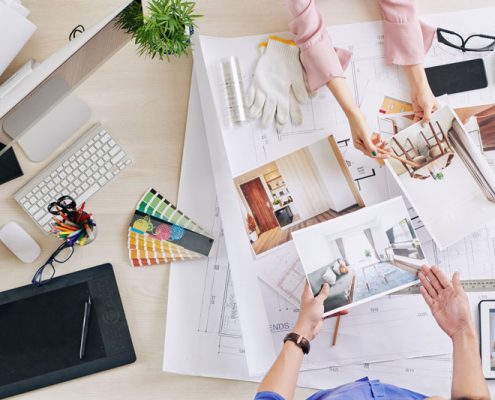 Deciding what home buyers really want. Two people at a table looking through home and furniture inspiration photos and colour schemes.