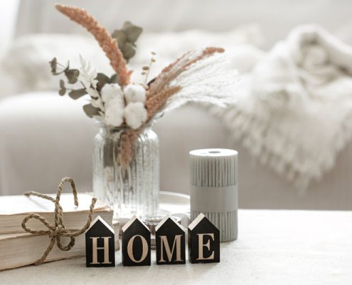 Design tips for renters. Coffee table infront of white couch with decorative elements on top. Blocks in foreground spelling home.