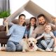 Pet-friendly home design for lovers of furry friends. Family sitting on loungue floor with a cardboard cut out of a house and dog laying in front of them.